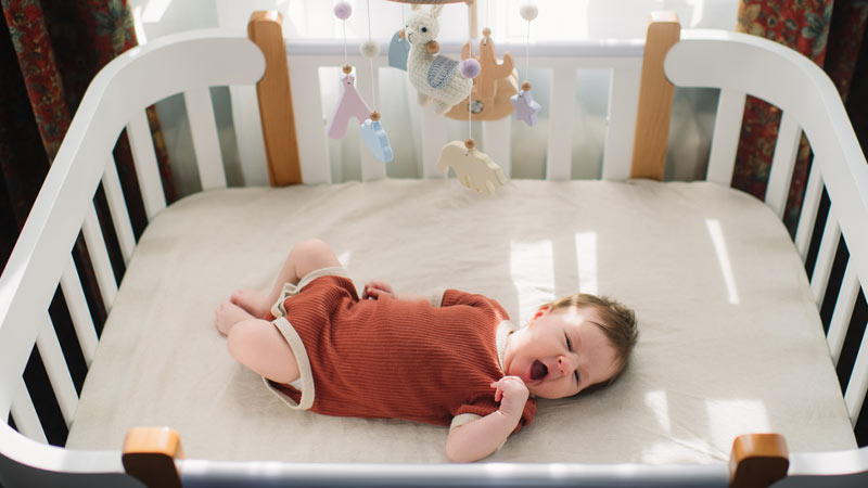 Bebé a dormir numa cama de grades